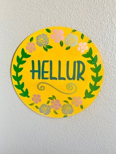 a yellow sign that says hellur with flowers and leaves painted on the side of it