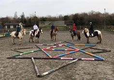 several people on horses are playing with sticks in the dirt while others stand around them