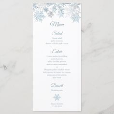 a white and pink menu card with snowflakes on the front, sitting on a marble surface