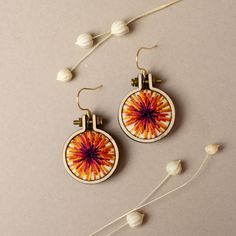 the earrings are decorated with an orange and red flower