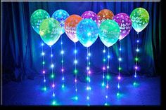 a bunch of balloons that have been lit up in the dark with lights on them