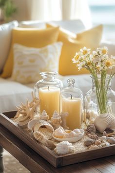 a tray with candles, shells and flowers sitting on a table in front of a couch