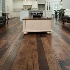 a kitchen and living room with hardwood flooring in an open concept home, which is well lit by pendant lights