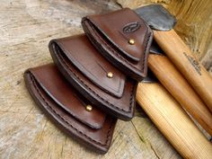 three leather wallets sitting next to each other on top of a piece of wood