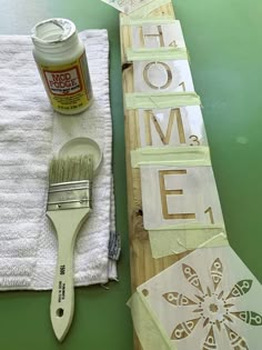 a paintbrush and some cut out letters on a wooden board next to a white towel