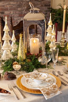 a table set for christmas dinner with candles and decorations