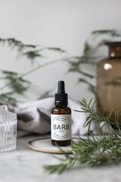 a bottle of beard oil sitting on top of a counter next to a glass vase