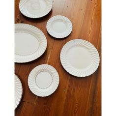 five white plates laid out on a wooden floor with one empty plate in the middle