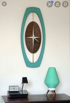 a clock mounted to the side of a wall next to a lamp on a table