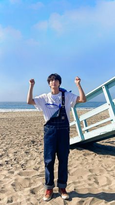 a young man standing on top of a sandy beach next to a lifeguard chair