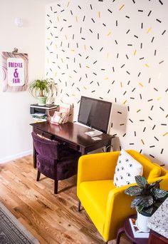 a living room filled with furniture and a computer on top of a wooden desk next to a yellow chair