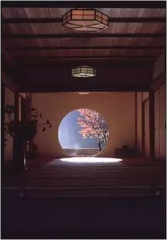 an empty room with a large circular window on the wall and trees in the background