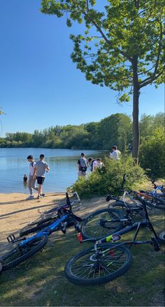 several people are standing near the water with their bikes