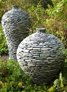 two large vases sitting in the middle of a garden