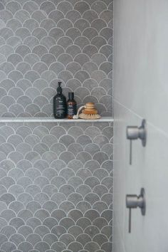 two bottles are sitting on the shelf next to each other in front of a shower