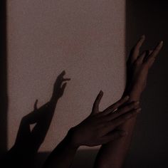 two hands reaching up to the ceiling with their shadow on the wall and one hand in the air