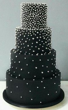 a three tiered cake with white polka dots on the bottom and black frosting