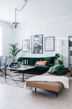 a living room with green couches and pictures on the wall above them, along with a coffee table