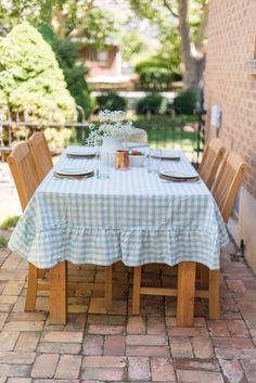 the table is set for two outside on the patio with blue and white checkered cloth