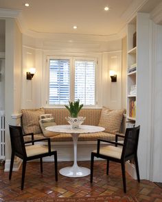 a living room with a couch, table and chairs around it in front of a bookshelf