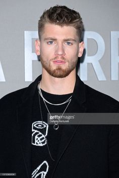 a man with a beard wearing a black shirt and silver chain necklace on his neck