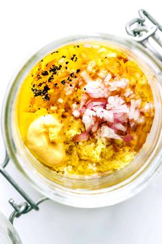 a glass jar filled with food on top of a white table next to utensils