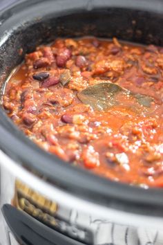 a slow cooker filled with chili, beans and meat is ready to be cooked