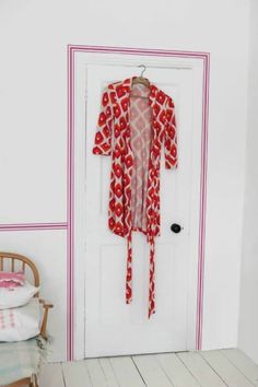 a white door with a red dress hanging on it's side next to a chair