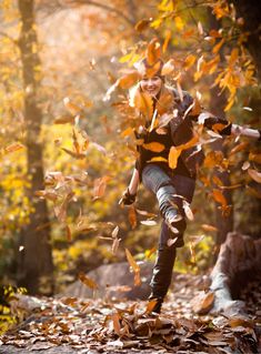 a young man is running through the leaves in an autumn forest with his arms outstretched