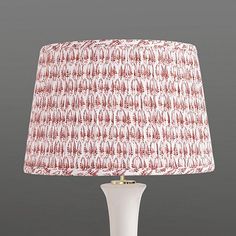 a white table lamp with a red and white fabric shade on the bottom of it