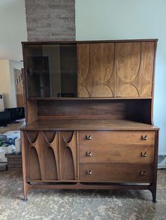 a wooden dresser with glass doors and drawers on it's sideboard in a living room