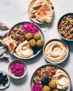 three bowls filled with different types of food on top of a table next to pita bread