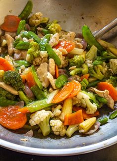 stir fried vegetables in a pan with tongs