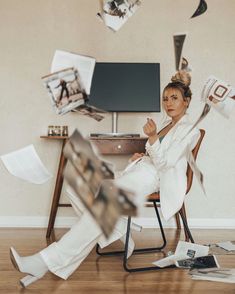 a woman sitting in a chair with papers flying around her