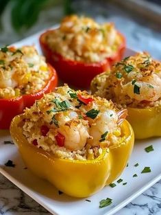 three stuffed bell peppers with shrimp and rice in them sitting on a white platter