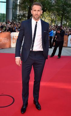 a man in a suit and tie standing on a red carpet