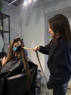 a woman getting her hair cut in a salon with another person watching from the side