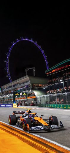 the red bull racing car in front of the london eye at night, as seen from behind