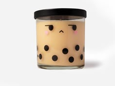 a candle with black dots on it and a face drawn on the front is in a glass container