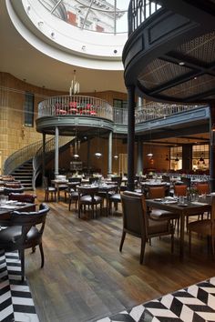 the inside of a restaurant with tables, chairs and spiral staircases on the second floor