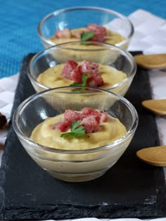 three small bowls filled with food on top of a black tray