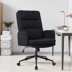 a black office chair sitting on top of a wooden desk next to a white wall