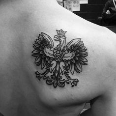 the back of a woman's shoulder with a tattoo design on it, depicting an eagle