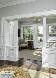 a living room filled with furniture and lots of white trim on the walls in front of windows