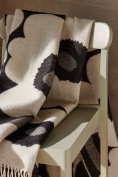 a black and white blanket sitting on top of a wooden chair next to a wall