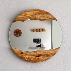 a circular mirror mounted to the side of a wall next to a wooden shelf with three corks on it