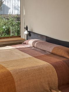 a bed sitting in a bedroom next to a window with a lamp on top of it