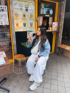 a woman sitting on a stool in front of a store