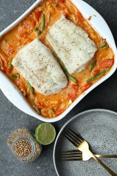 two enchiladas in a white casserole dish with lime wedges