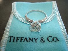 a tiffany and co ring sits on top of a blue cloth with the tiffany & co logo